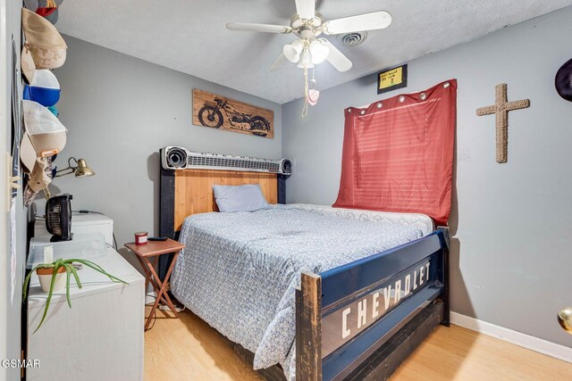 bedroom with hardwood / wood-style flooring, ceiling fan, and a textured ceiling