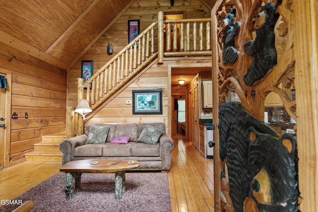 living area with wood walls, lofted ceiling, light wood-type flooring, stairway, and wood ceiling
