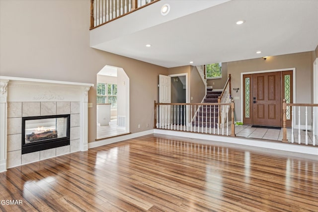 unfurnished living room with a tiled fireplace and light wood-type flooring