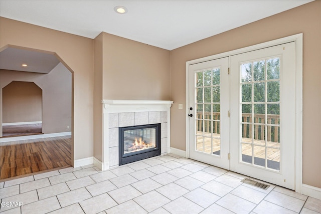 unfurnished living room featuring a tile fireplace and light tile patterned flooring