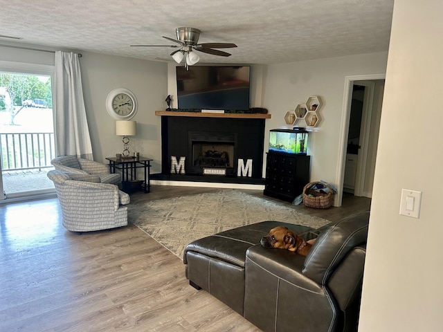 living room featuring hardwood / wood-style floors, ceiling fan, and a textured ceiling