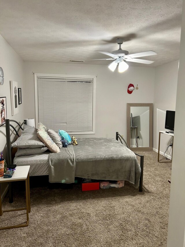 bedroom featuring carpet flooring, ceiling fan, and a textured ceiling