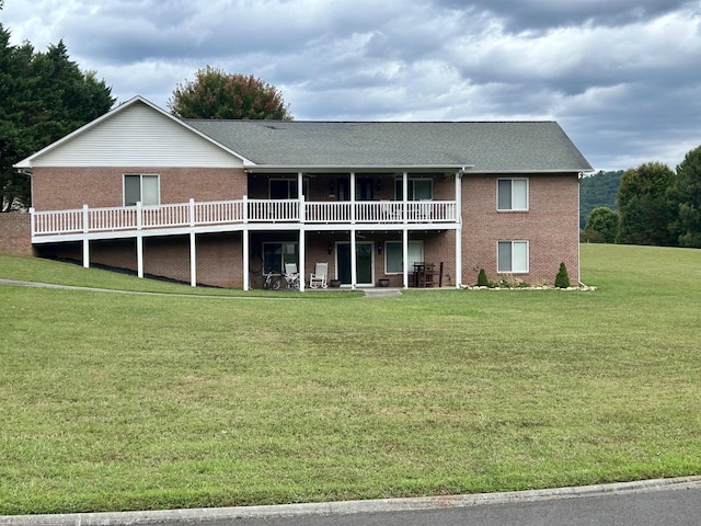 rear view of house with a lawn and a wooden deck