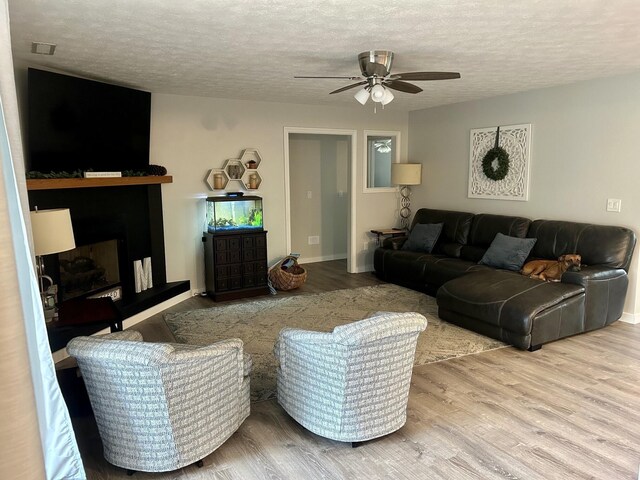 living room with ceiling fan, wood-type flooring, and a textured ceiling