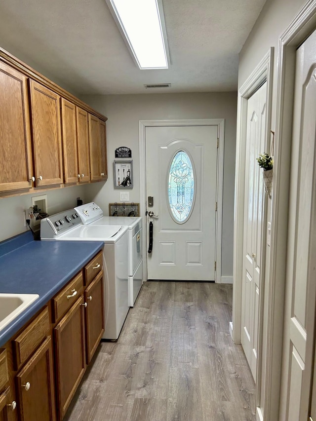 laundry room featuring cabinets, separate washer and dryer, and light hardwood / wood-style flooring