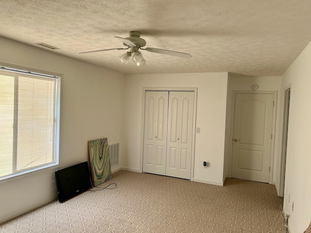 unfurnished bedroom featuring multiple windows, a textured ceiling, a closet, and ceiling fan