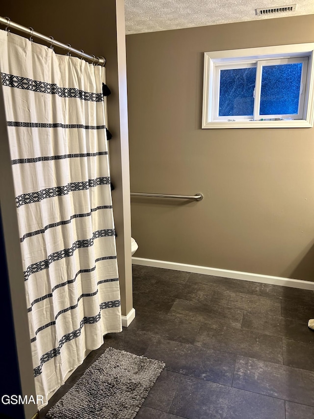 full bath with baseboards, curtained shower, toilet, and a textured ceiling