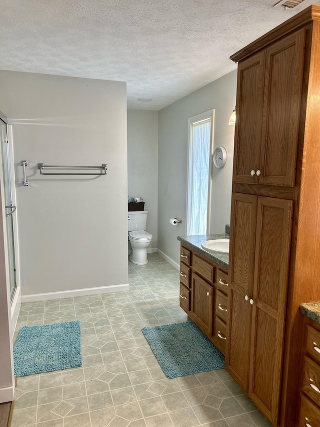 bathroom featuring walk in shower, vanity, a textured ceiling, and toilet