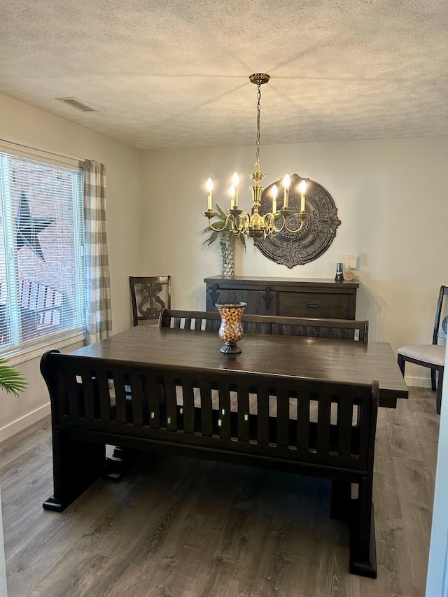 dining space featuring a notable chandelier, wood-type flooring, and a textured ceiling