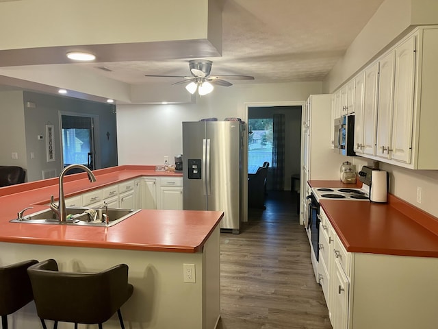 kitchen with ceiling fan, sink, stainless steel appliances, kitchen peninsula, and a breakfast bar area