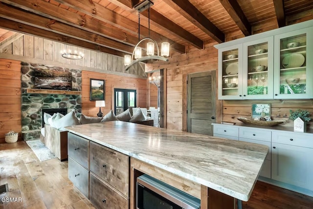 4427 Stackstone Rd, Sevierville, TN 37862 - kitchen with wood ceiling with exposed beams, wood walls, light wood finished floors, open floor plan, and a stone fireplace