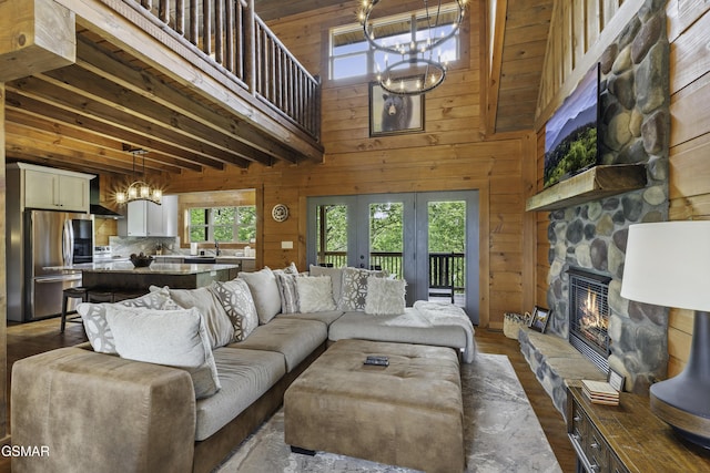 4427 Stackstone Rd, Sevierville, TN 37862 - living area with a chandelier, a stone fireplace, wooden walls, a towering ceiling, and dark wood-type flooring