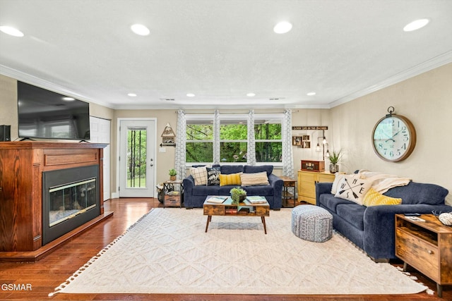 living area with a glass covered fireplace, recessed lighting, dark wood-style floors, and ornamental molding