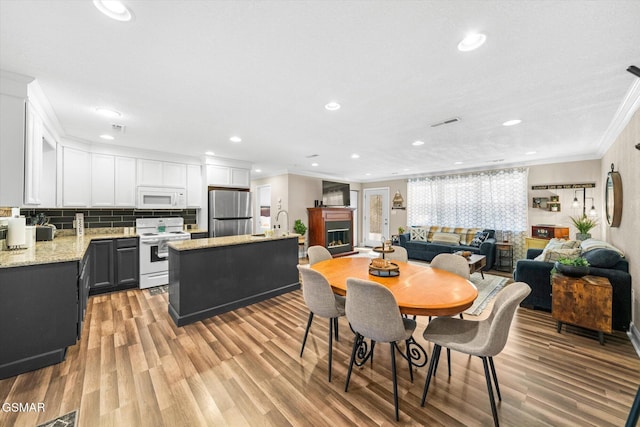 dining area featuring light wood finished floors, visible vents, ornamental molding, recessed lighting, and a fireplace