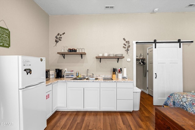 kitchen featuring dark wood finished floors, visible vents, freestanding refrigerator, and a sink