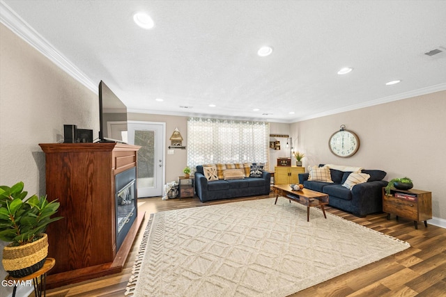 living room featuring visible vents, ornamental molding, and wood finished floors