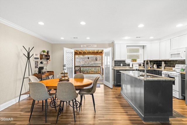 kitchen featuring ornamental molding, a sink, wood finished floors, white appliances, and decorative backsplash