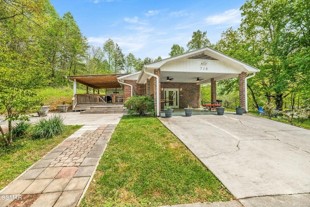 rear view of house with a lawn, covered porch, ceiling fan, and brick siding