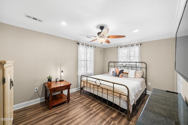 bedroom featuring visible vents, baseboards, wood finished floors, and ornamental molding