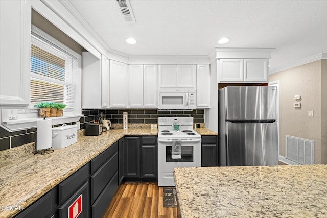 kitchen with visible vents, white appliances, white cabinets, and ornamental molding