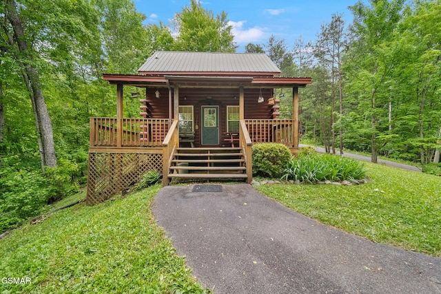 view of front of house with log siding, covered porch, and metal roof