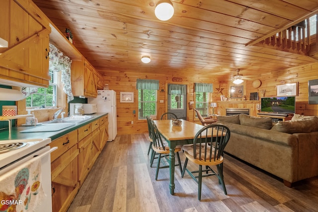 kitchen with wooden ceiling, a fireplace, white appliances, wooden walls, and light wood-style floors