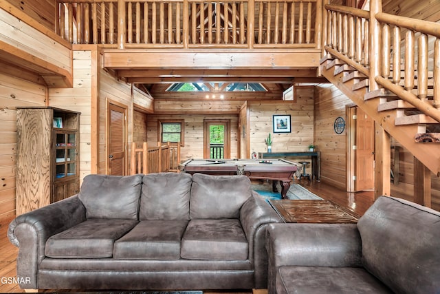 living room featuring hardwood / wood-style flooring, wood walls, a towering ceiling, and pool table