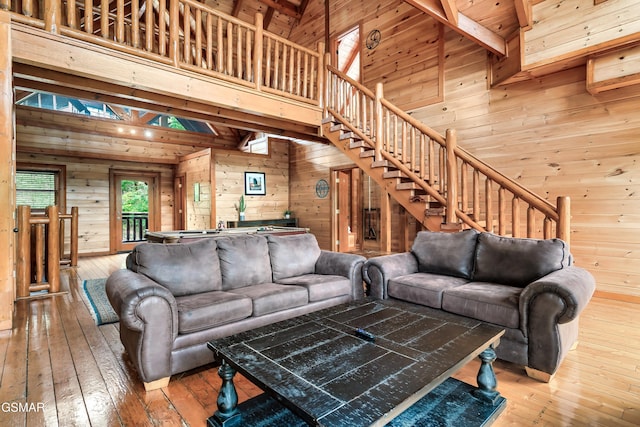 living room with wood ceiling, wooden walls, hardwood / wood-style flooring, high vaulted ceiling, and beamed ceiling