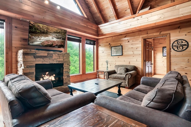 living room with wood ceiling, beam ceiling, high vaulted ceiling, a stone fireplace, and wood walls