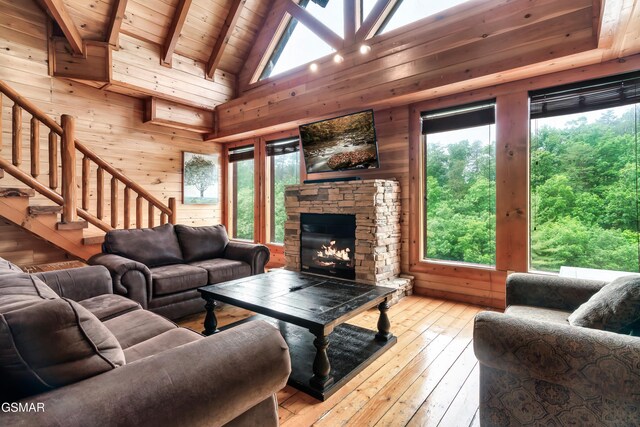 living room with light wood-type flooring, wood ceiling, beam ceiling, high vaulted ceiling, and a fireplace