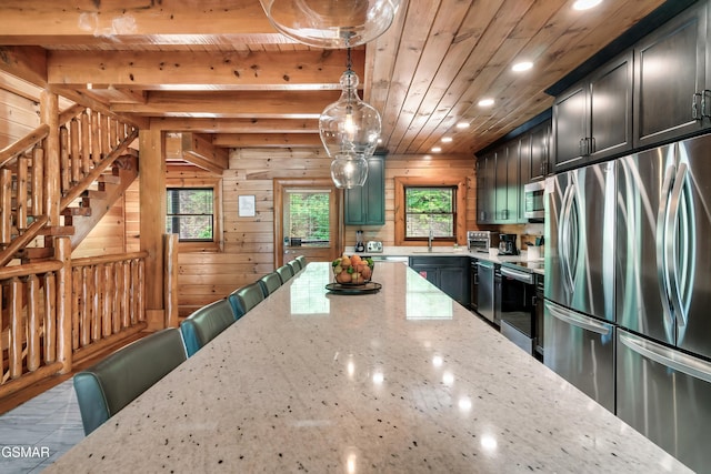 kitchen with wooden ceiling, wooden walls, light stone countertops, decorative light fixtures, and stainless steel appliances