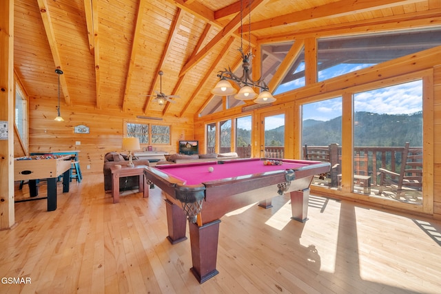 playroom with wooden walls, vaulted ceiling with beams, a mountain view, wooden ceiling, and light hardwood / wood-style flooring