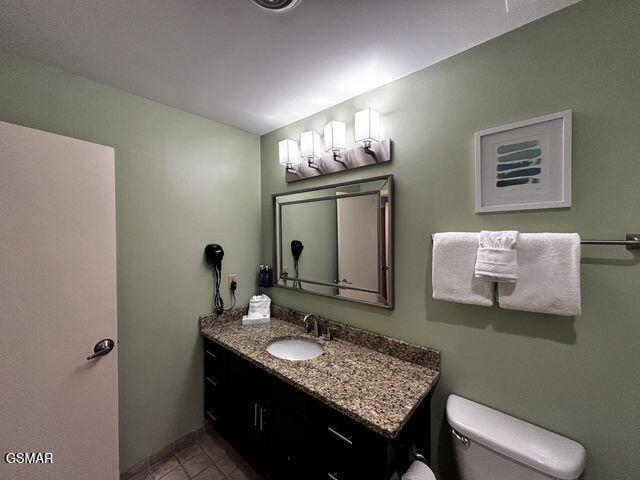 bathroom featuring toilet, tile patterned floors, baseboards, and vanity