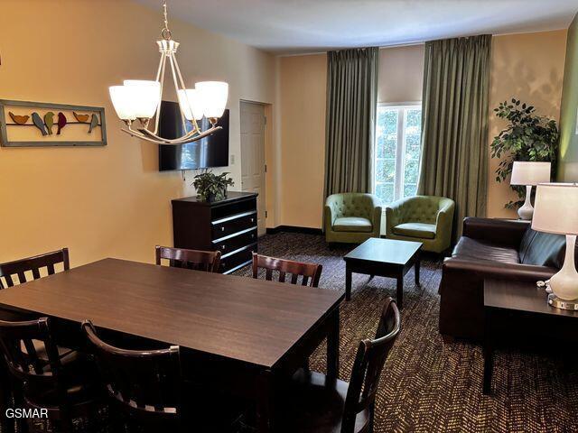 dining space with a chandelier and dark carpet