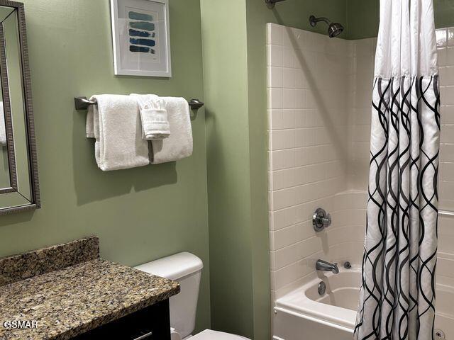 full bathroom featuring shower / bathtub combination with curtain, toilet, and vanity