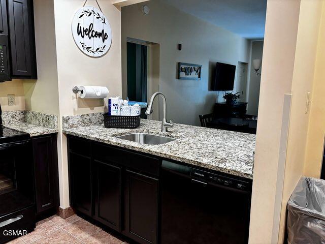 kitchen with light tile patterned flooring, a sink, black appliances, and light stone countertops