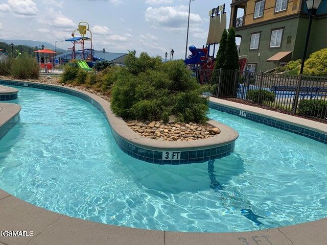 view of pool featuring fence and playground community