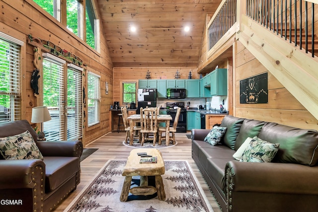 living area featuring wooden walls, high vaulted ceiling, light wood-type flooring, and wooden ceiling