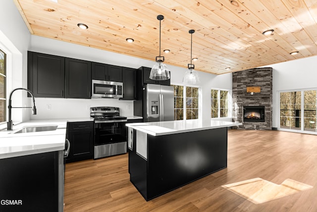 kitchen featuring appliances with stainless steel finishes, decorative light fixtures, sink, a center island, and wooden ceiling