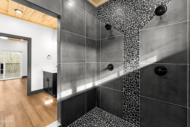 bathroom with hardwood / wood-style floors, vanity, a tile shower, and wooden ceiling