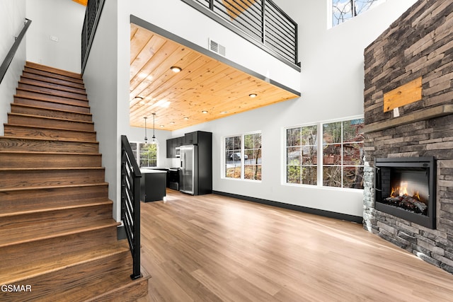 stairway with hardwood / wood-style flooring, a towering ceiling, a fireplace, and wood ceiling