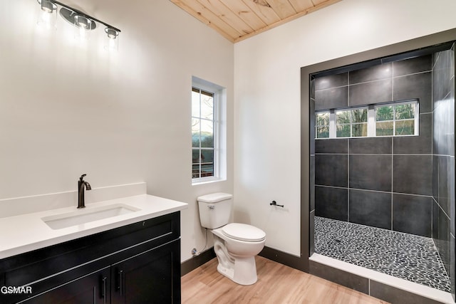 bathroom with a tile shower, hardwood / wood-style flooring, vanity, toilet, and wooden ceiling