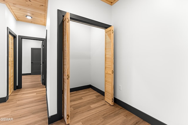 corridor featuring light wood-type flooring and wooden ceiling