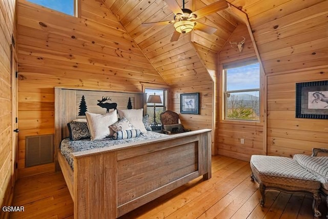 bedroom with light wood-type flooring, wooden walls, and vaulted ceiling