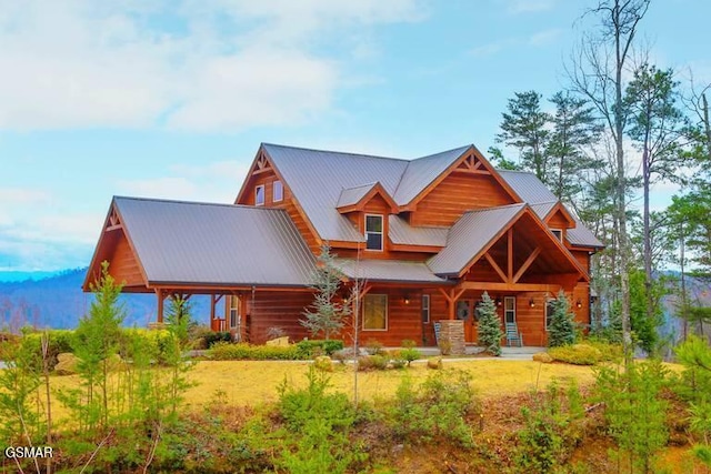 log-style house featuring a porch, metal roof, and a front lawn