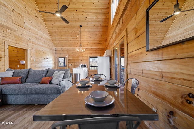 dining space featuring a notable chandelier, wood walls, hardwood / wood-style flooring, wood ceiling, and high vaulted ceiling