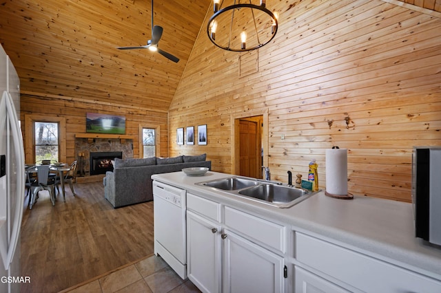 kitchen featuring white appliances, white cabinetry, sink, wood walls, and high vaulted ceiling