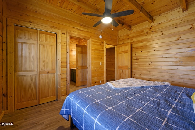 bedroom featuring ceiling fan, beam ceiling, wooden walls, wood ceiling, and a closet