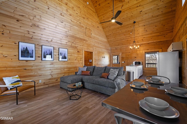 living room featuring wood walls, hardwood / wood-style floors, wood ceiling, high vaulted ceiling, and ceiling fan with notable chandelier