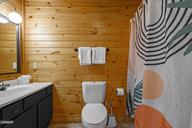 bathroom with toilet, vanity, tile patterned flooring, wooden walls, and a shower with shower curtain